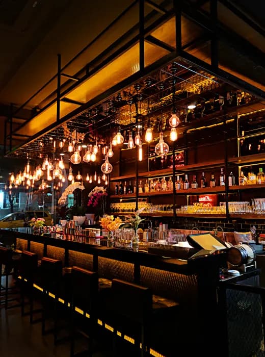 A back bar of spirits under warm hanging bulbs